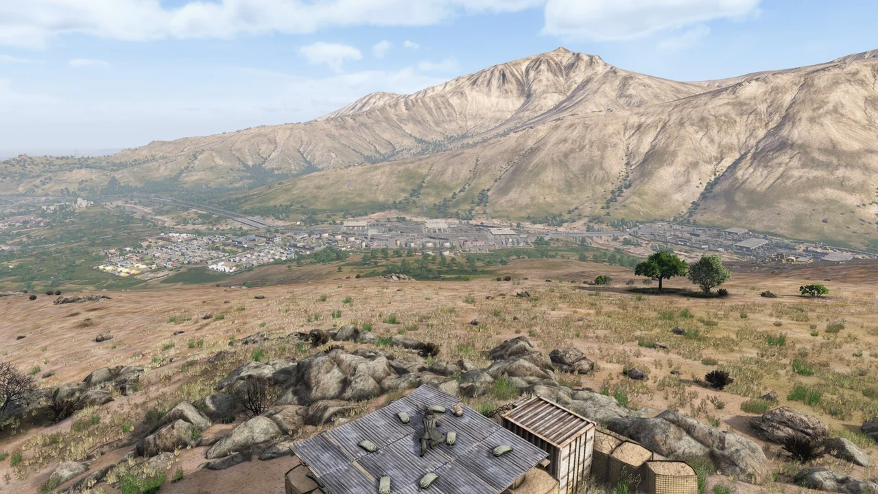 Arid Nasdara valley with scattered rooftops and a distant town under a hazy sky
